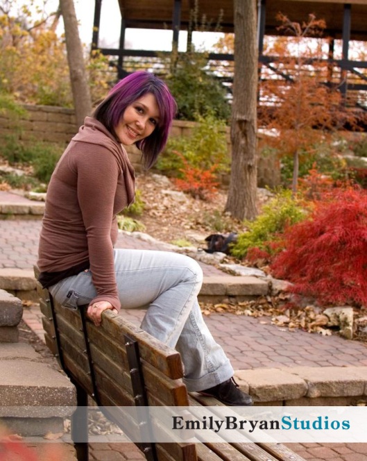 Smiling young woman sitting on top of a park bench.