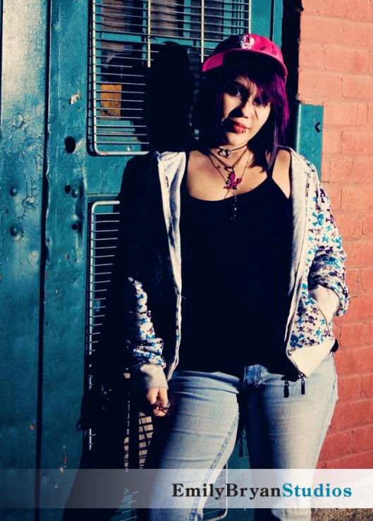 Young woman wearing a hat and sweatshirt leaning on a door.