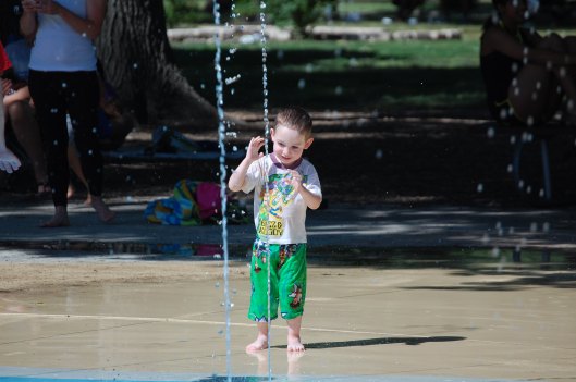 Eli Bryan looking at a squirting stream of water at Splash Park