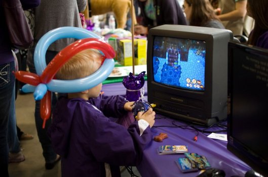 Boy wearing a baloon animal hat playing a video game.