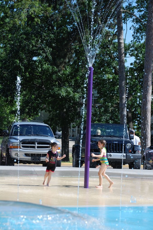 Emma Bryan and her friend playing tag under a water fountain.